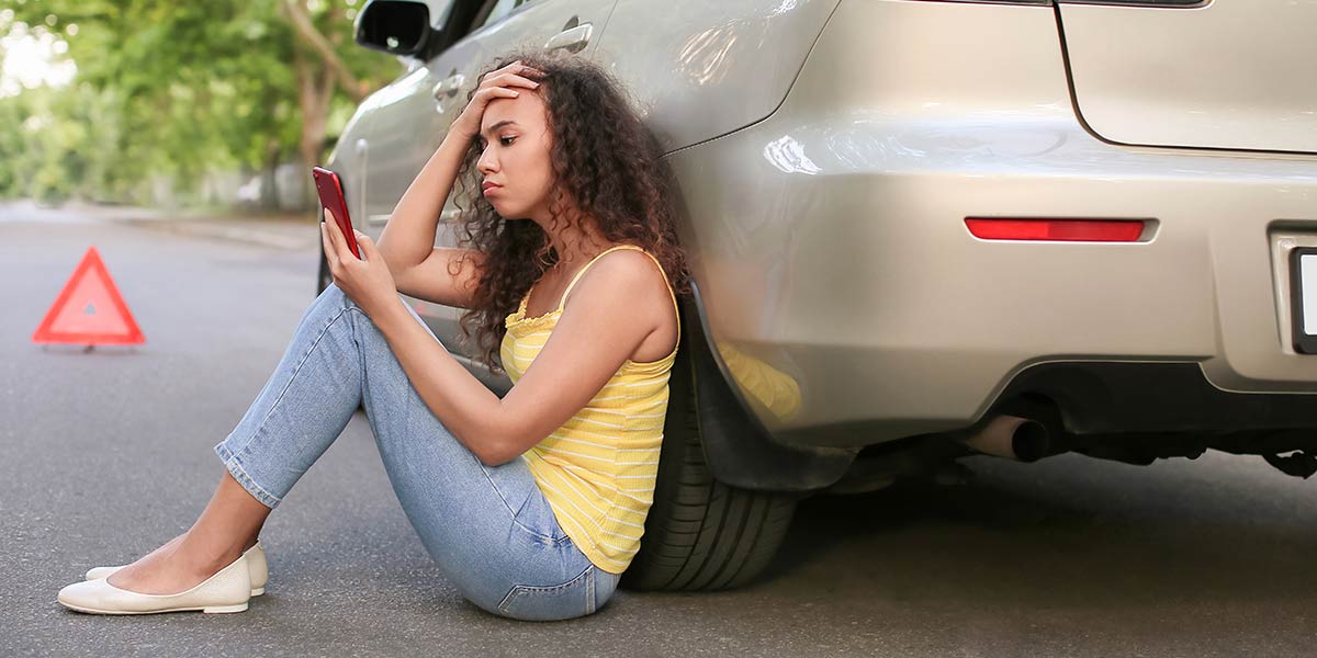 Woman looking at her phone after her car broke down