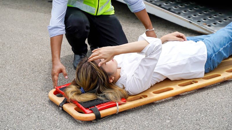 | Matz Injury Law Paramedic assists injured person on stretcher during emergency response, focusing on care and safety.