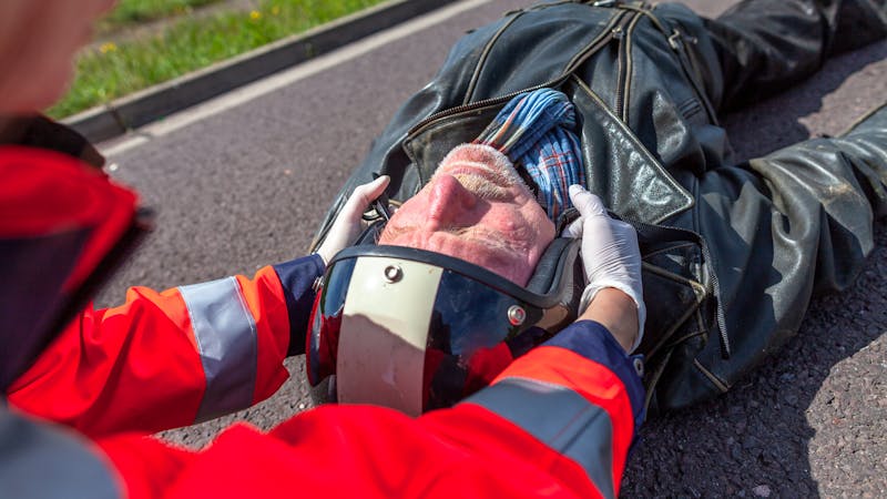 A paramedic removes an helmet from an injured biker.