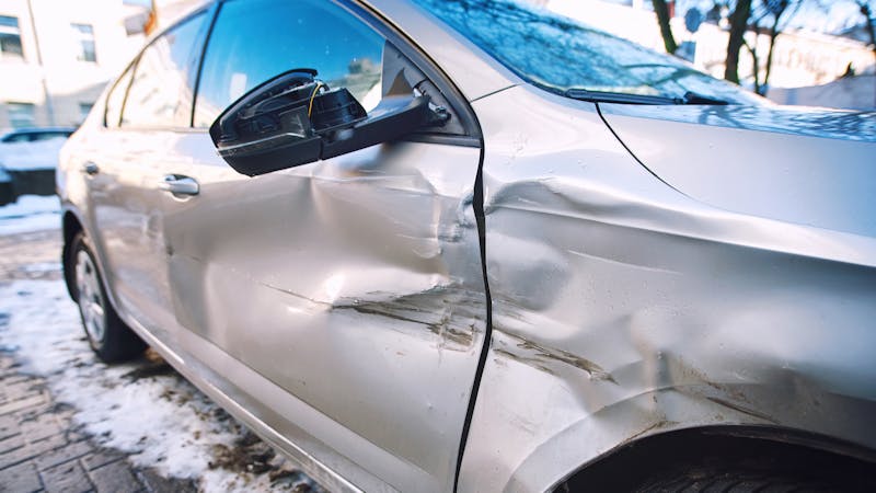 Grey sedan with damage to the front quarter panel