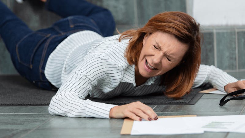 Woman falling on ground with papers strewn around her