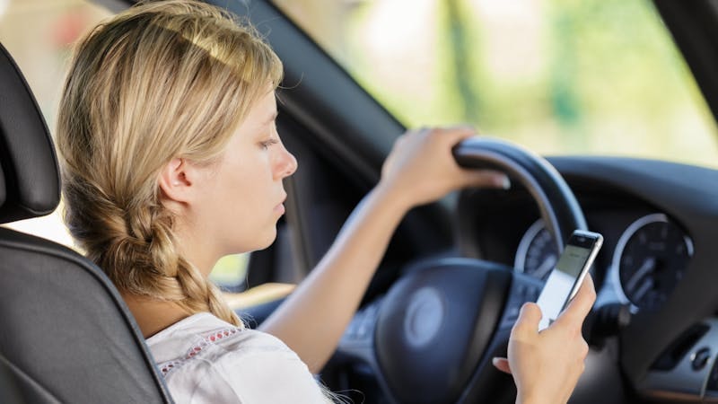Woman texting and driving behind the wheel