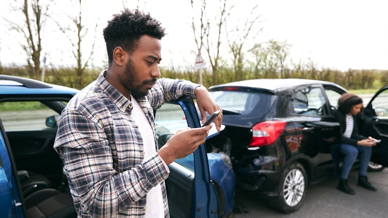 Man texting on his phone after a rear end accident