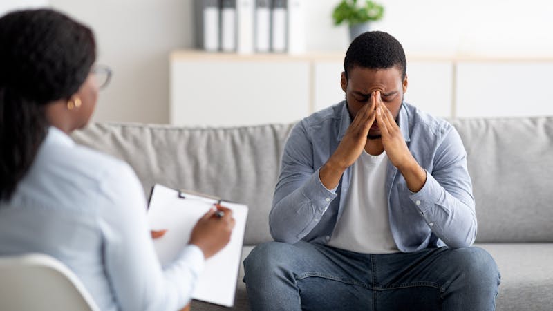 PTSD victim sitting on a couch speaking with his counselor 