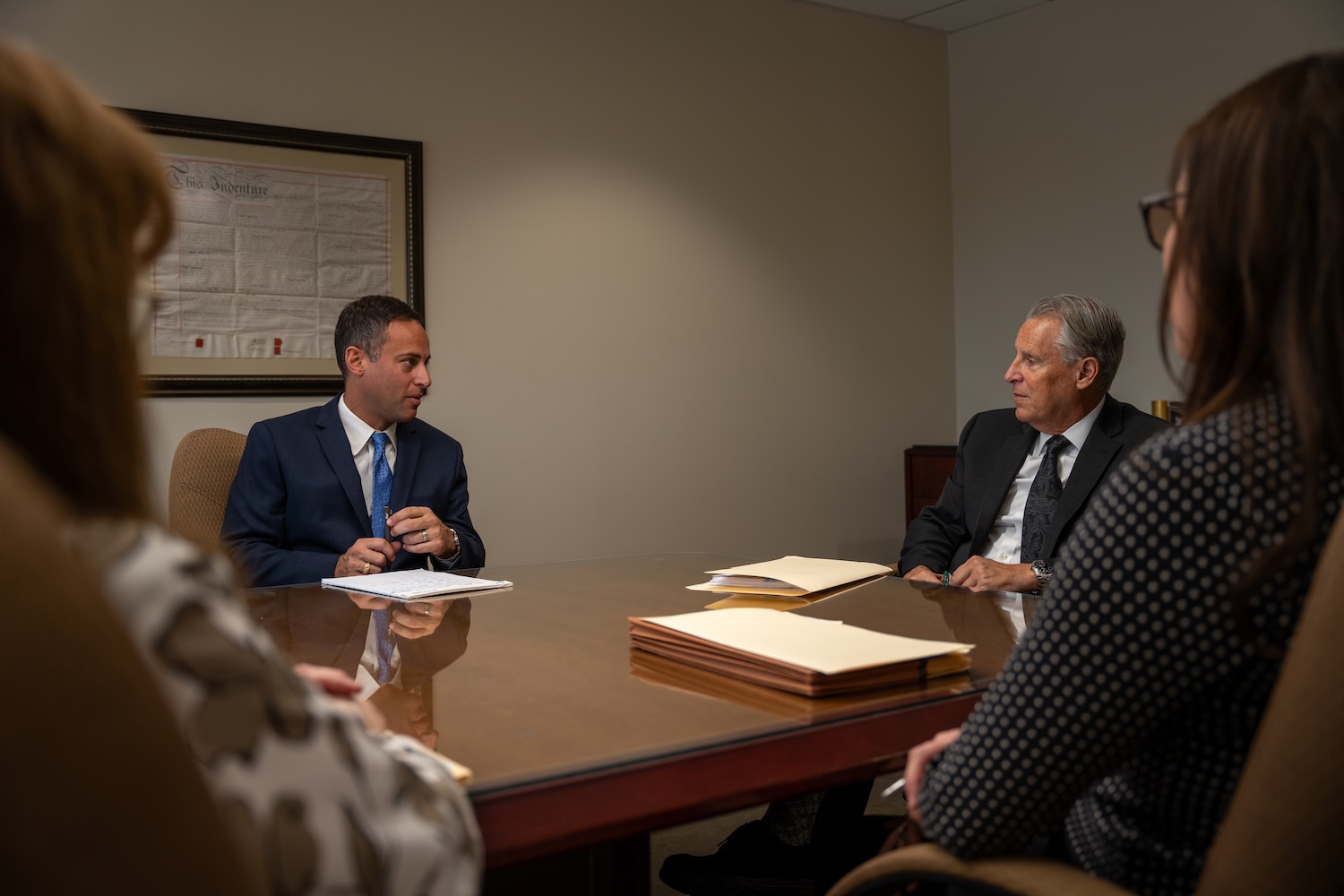 Business meeting in conference room with four professionals discussing documents.