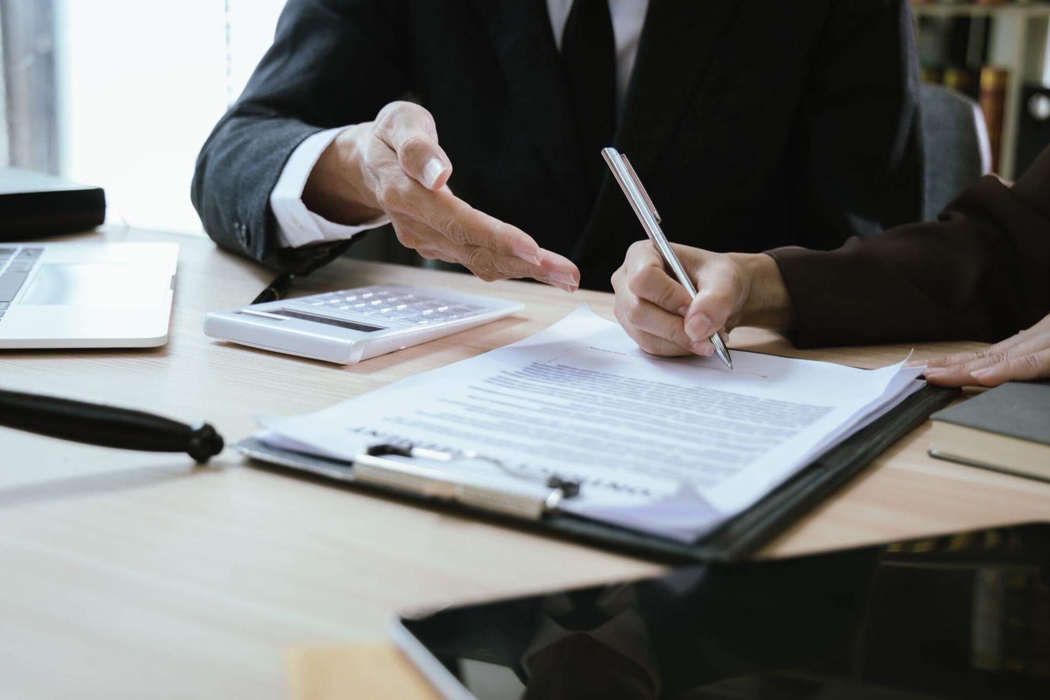 A man in a suit signing legal documents related to a car accident settlement