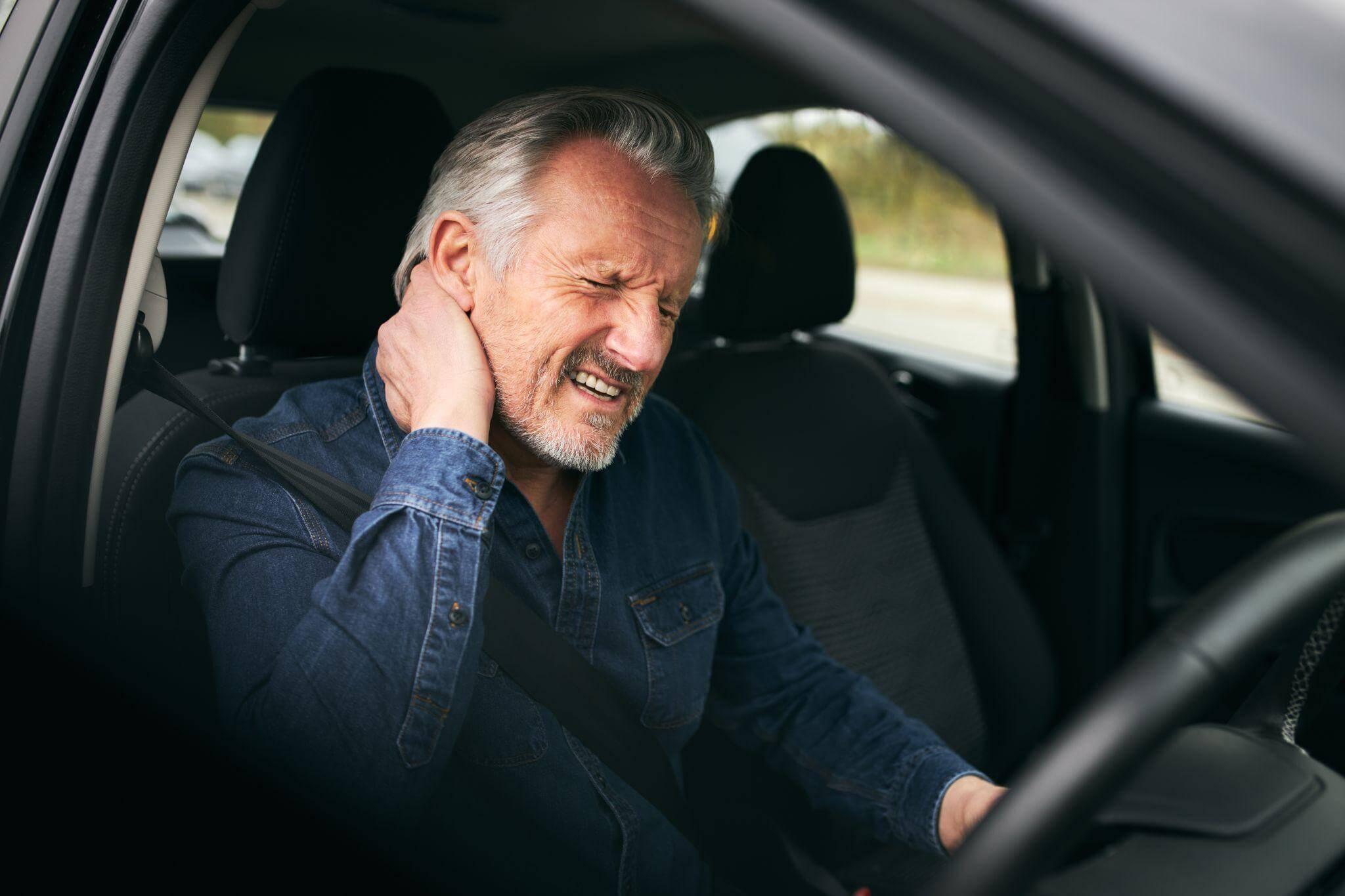 a man sitting in a car with his hand on his ear