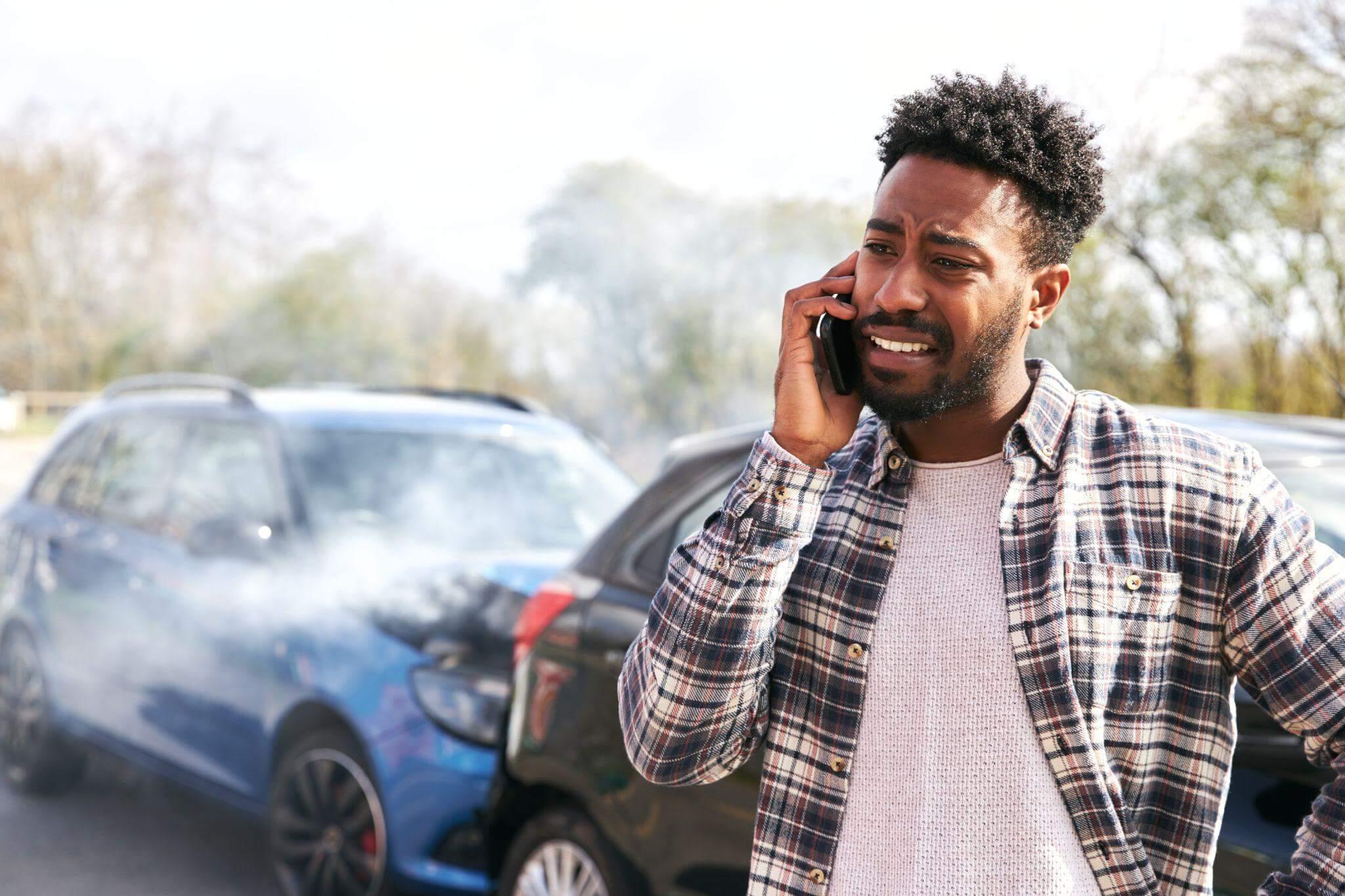 a man talking on a cell phone next to a car