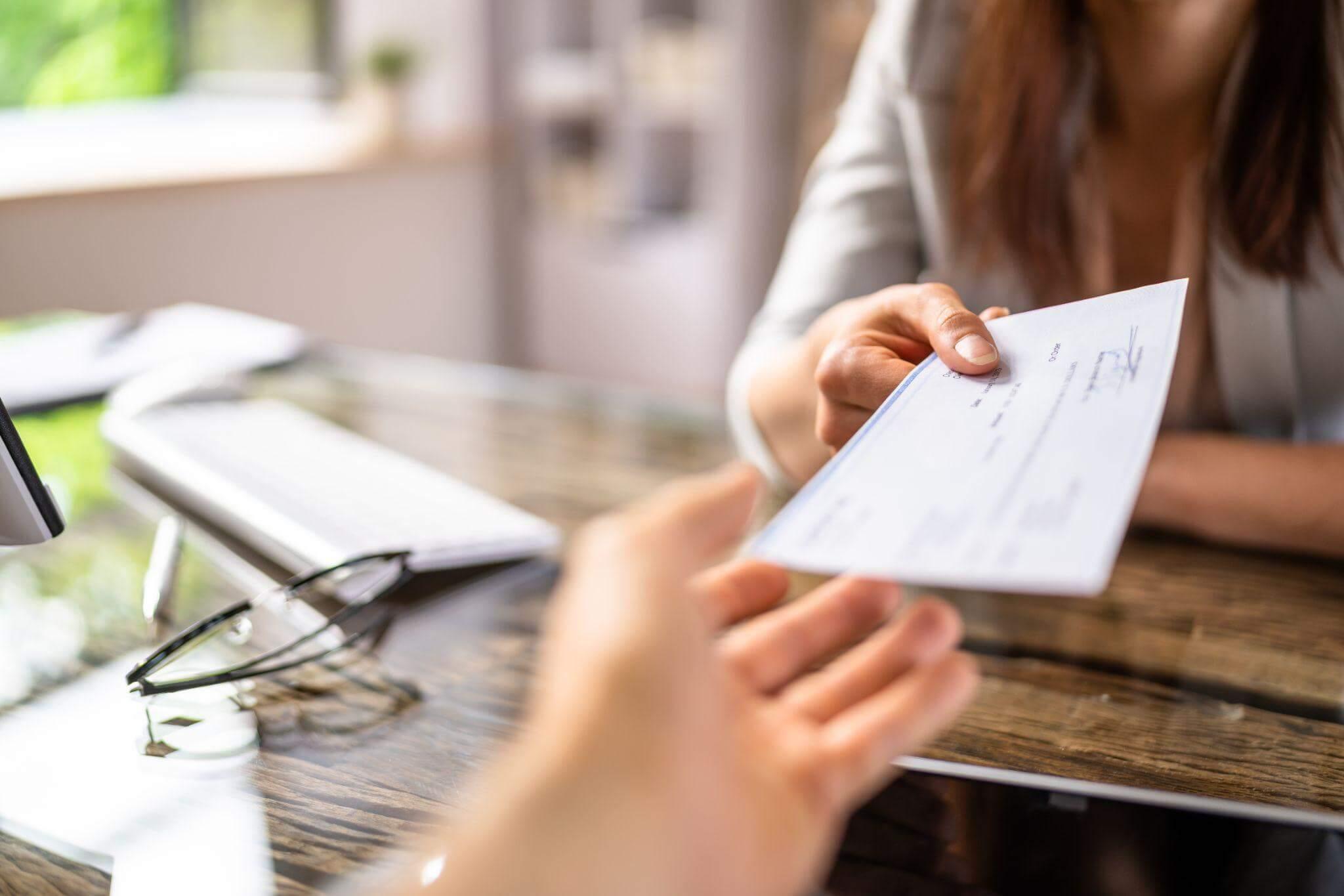 a person handing a check to another person at a desk