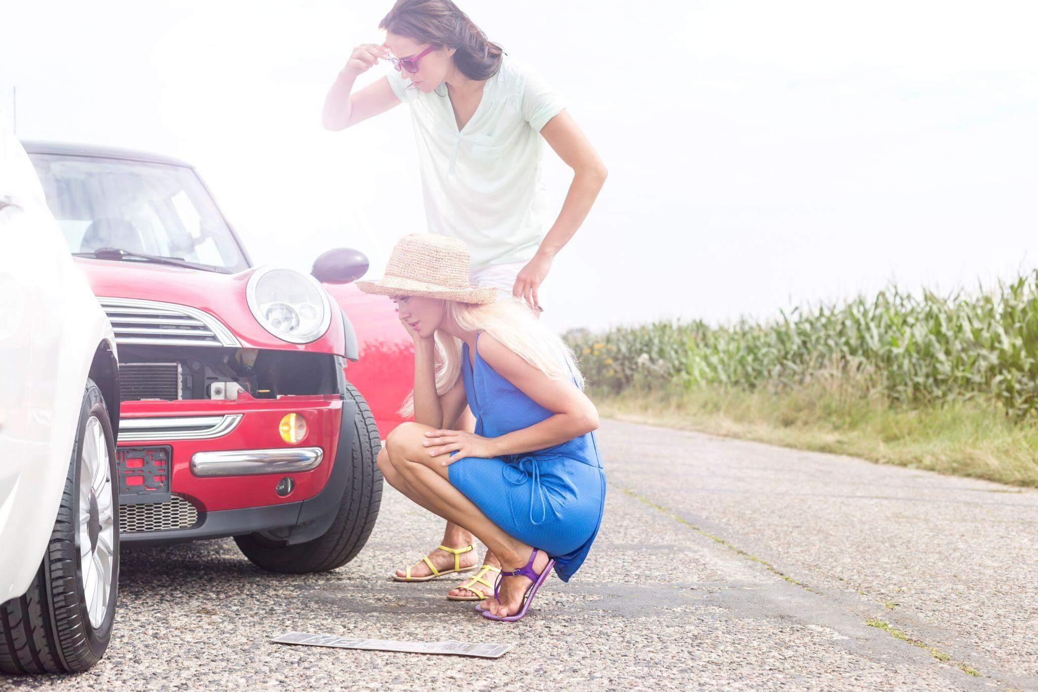 a woman kneeling down next to a red car