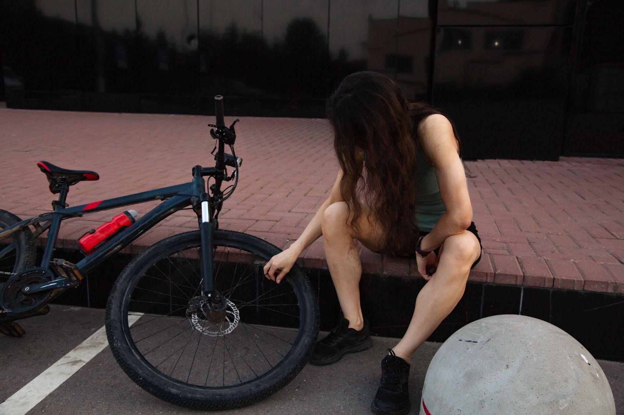 a woman sitting on the ground next to a bike