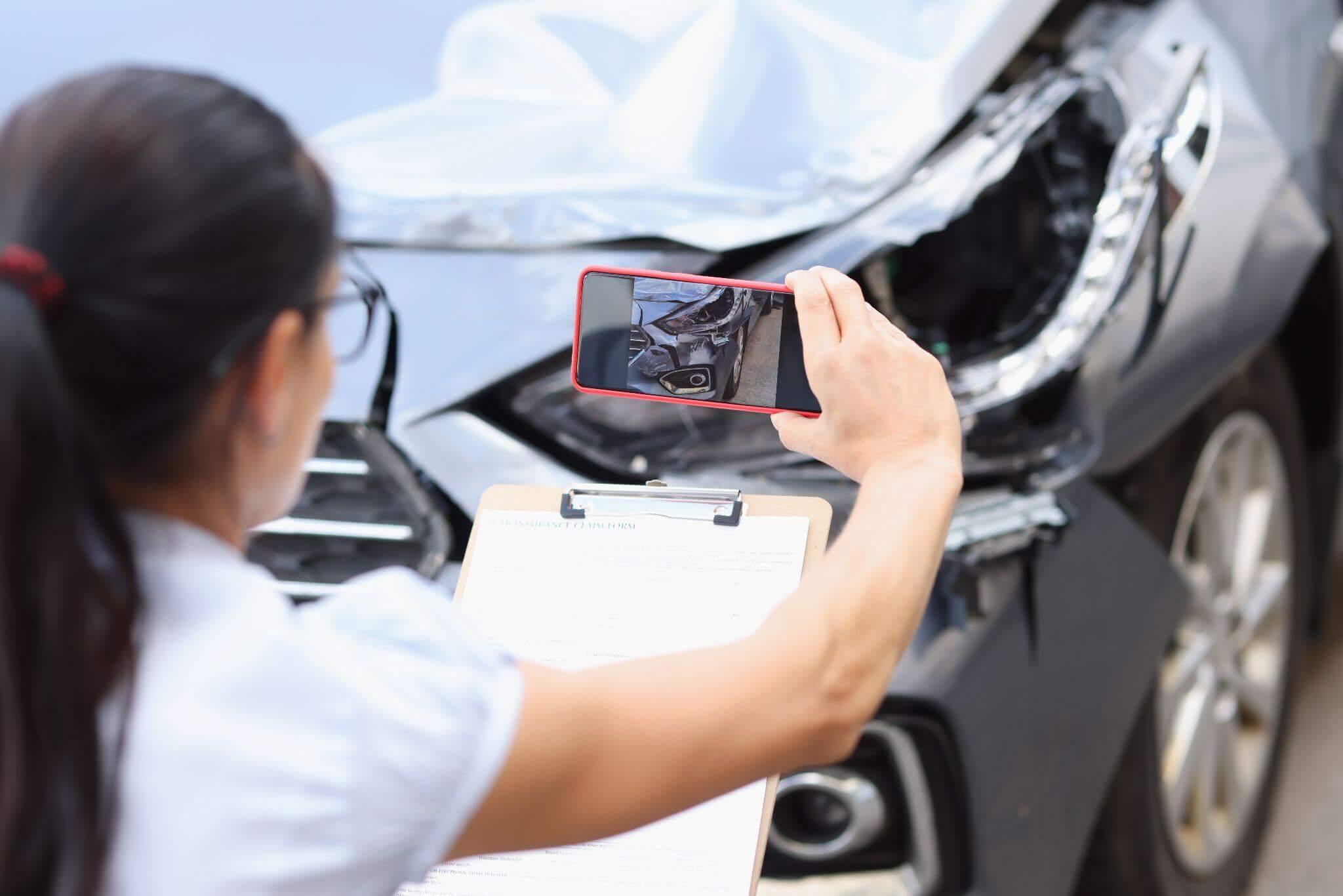 a woman taking a picture of a damaged car