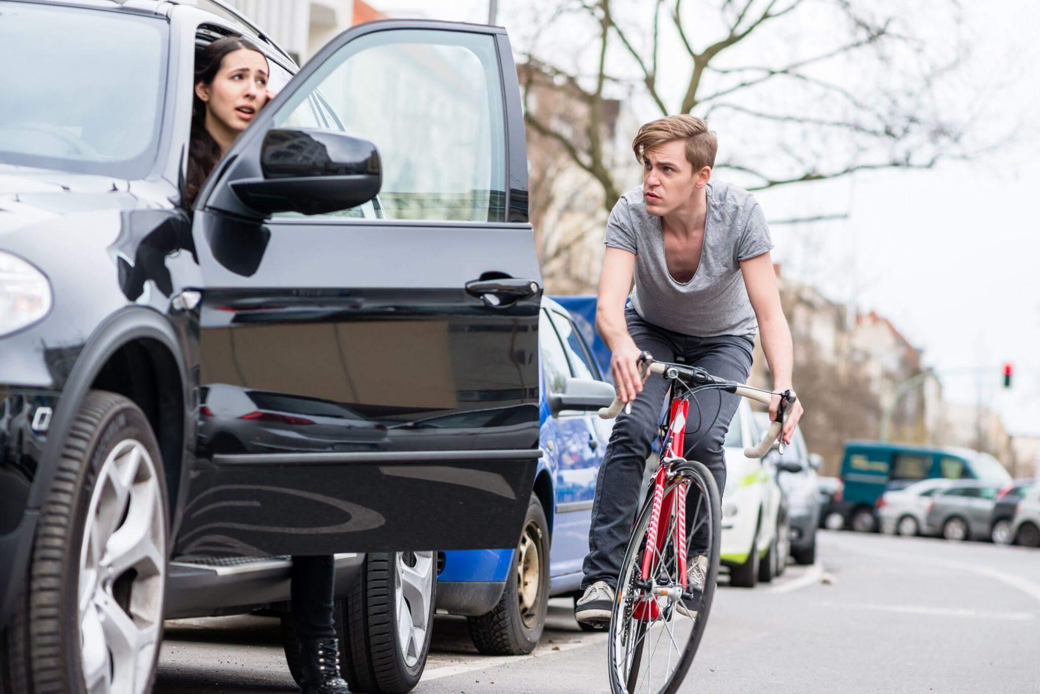a man riding a bike next to a parked car