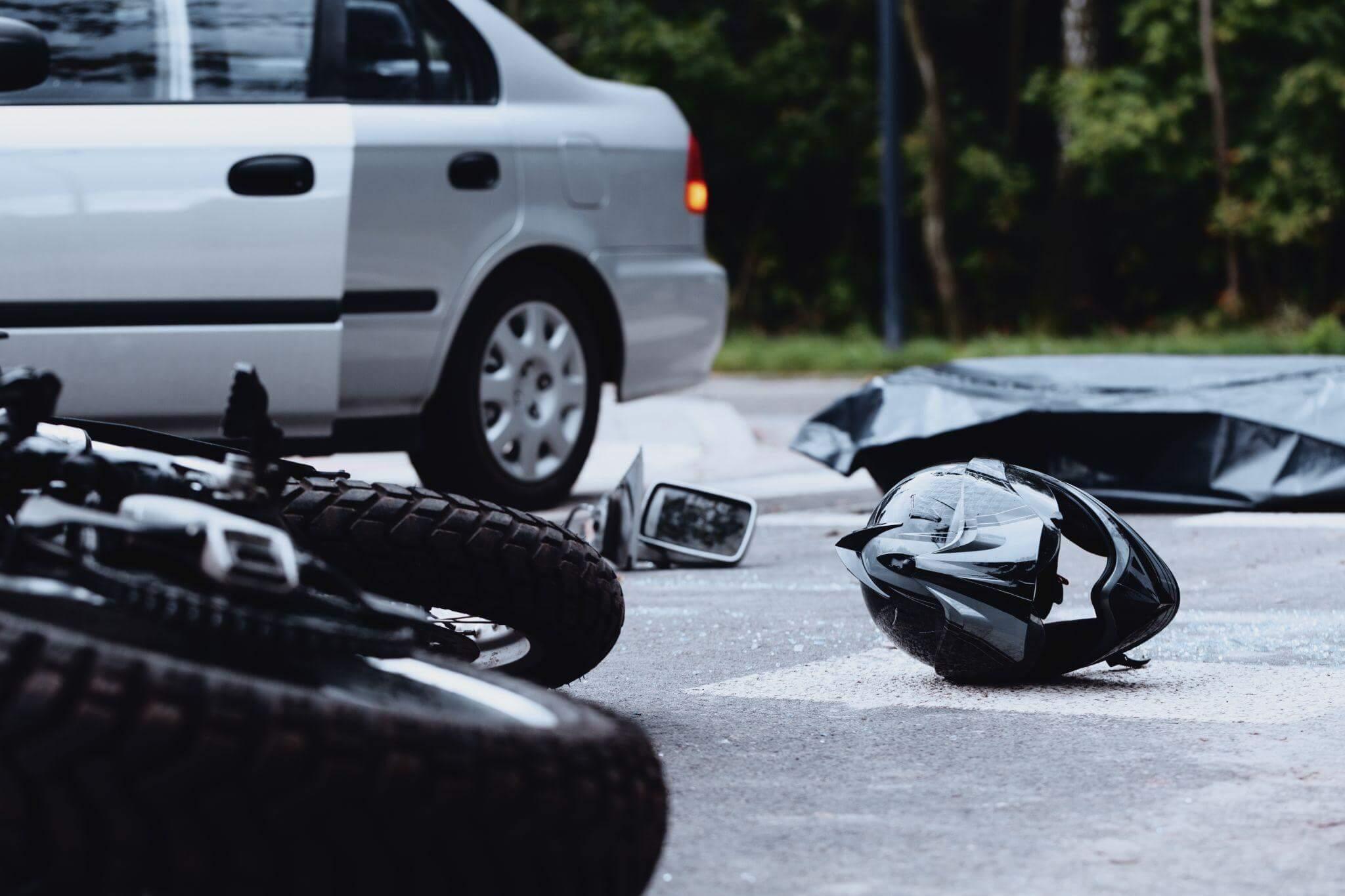 Motorcycles and car parked on city street after an accident, there's a helmet on the ground