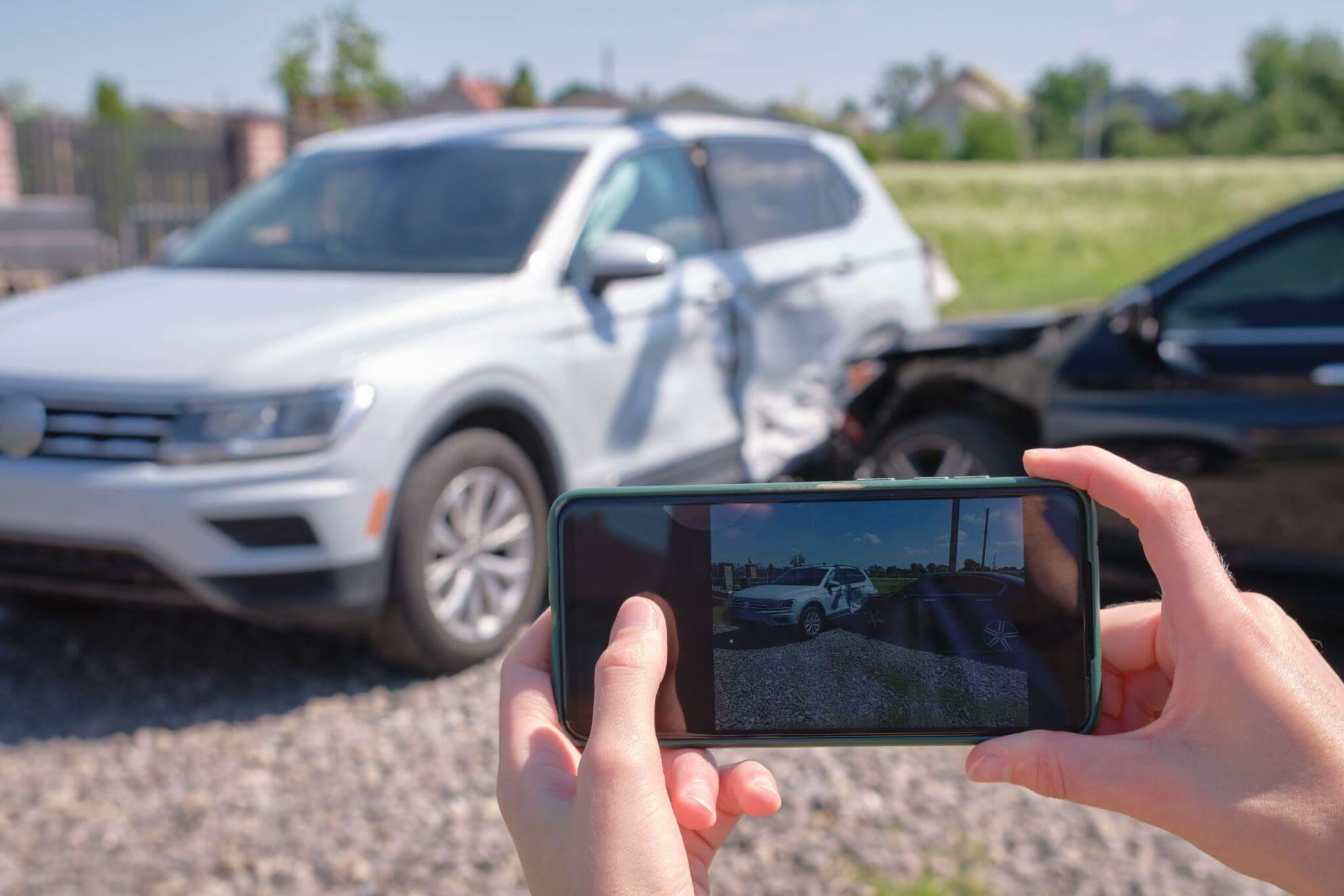 Person photographing cars with smartphone, the background scene depicts two car having recently collided