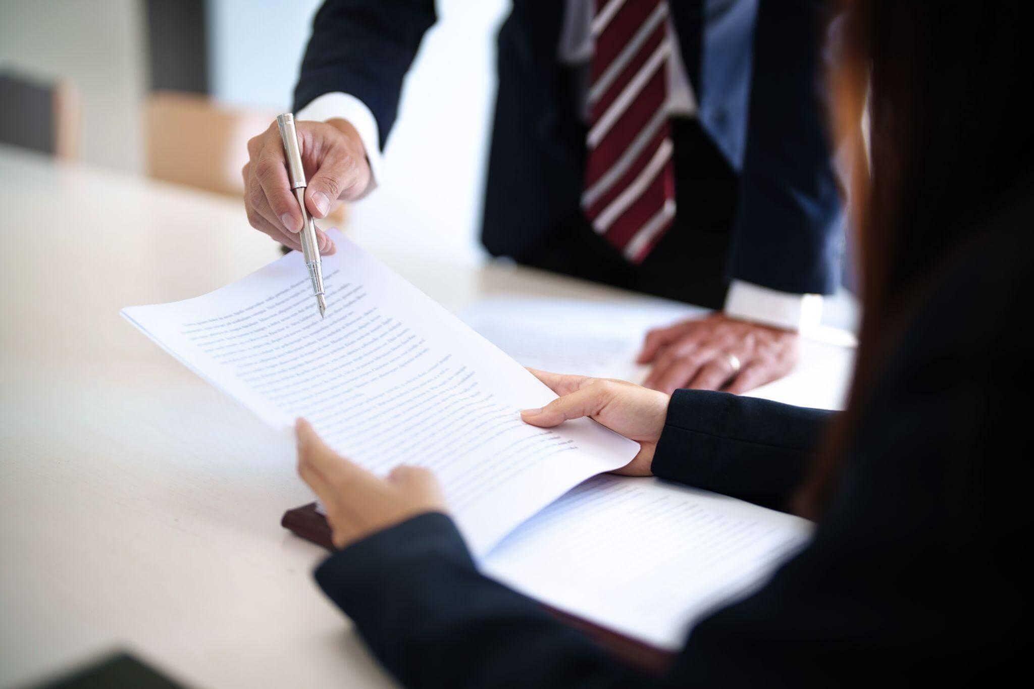 Two people signing documents at a table