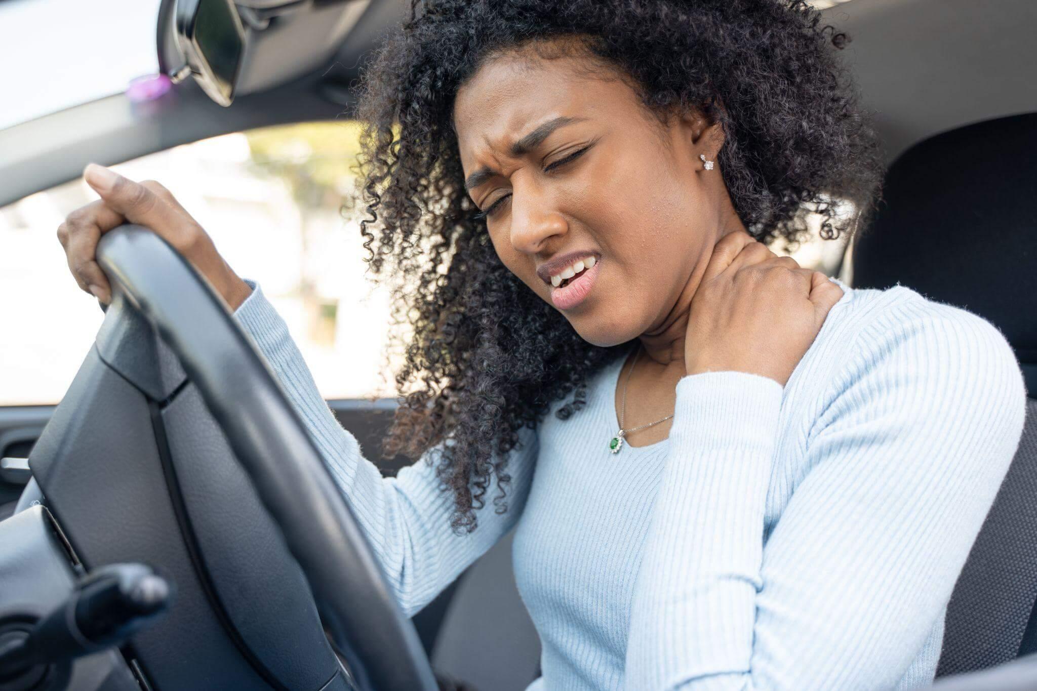 Woman experiencing neck pain while driving after car accident