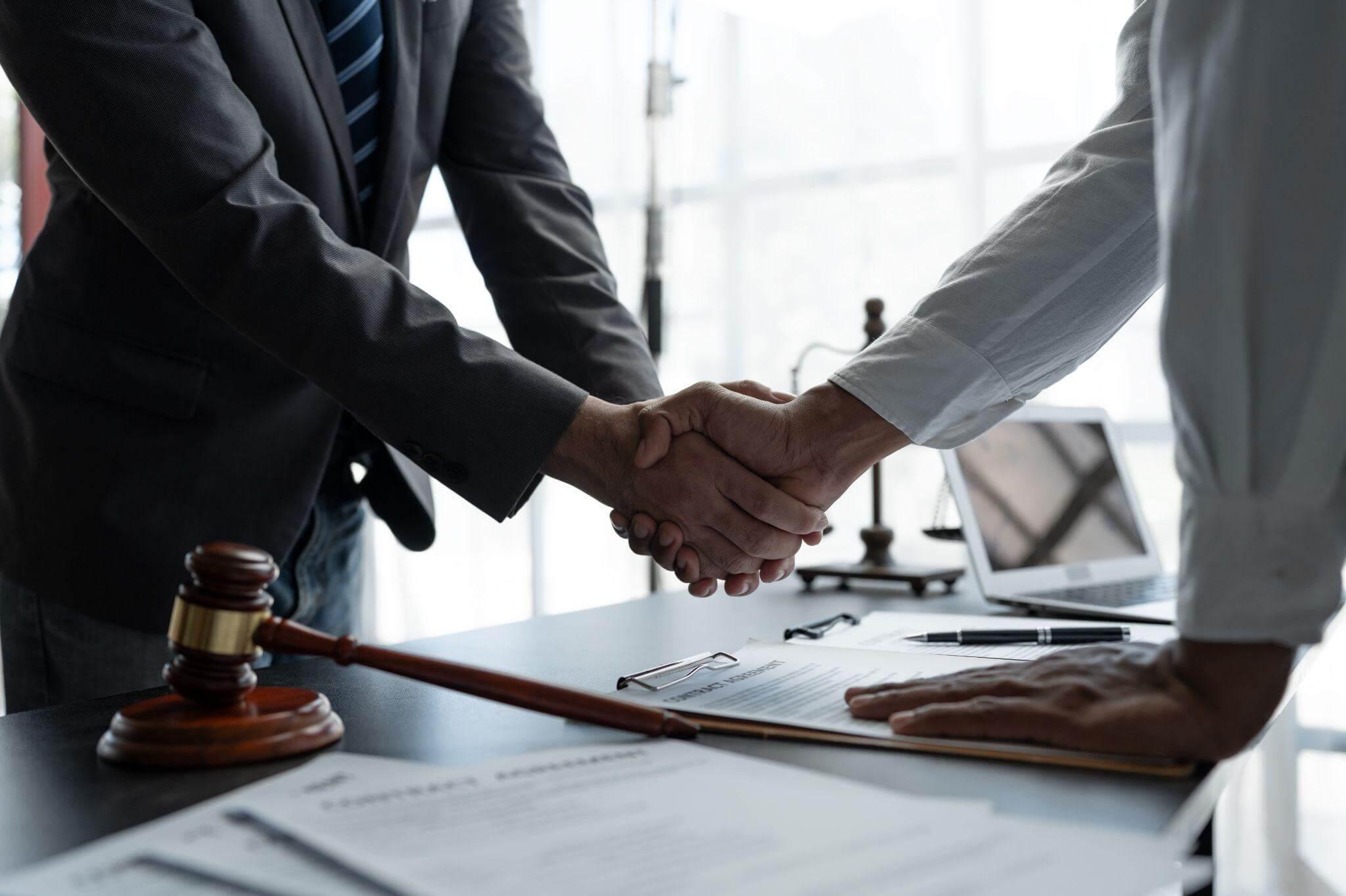 a couple of people shaking hands over a desk