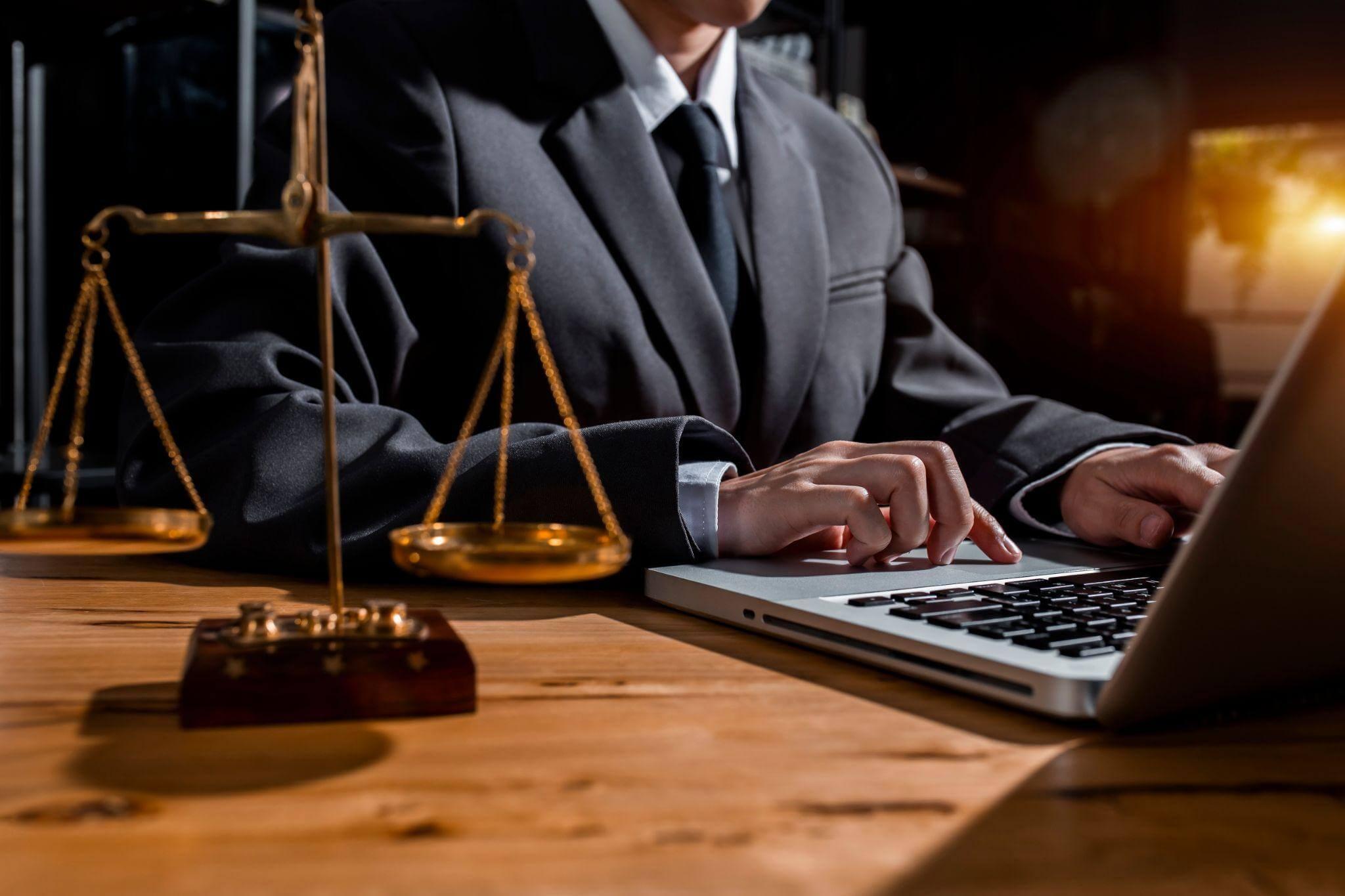 a man in a suit sitting in front of a laptop computer