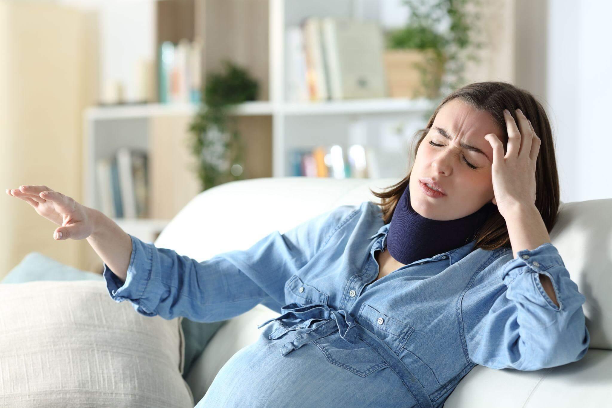 a woman sitting on a couch holding her head indicating she is in pain