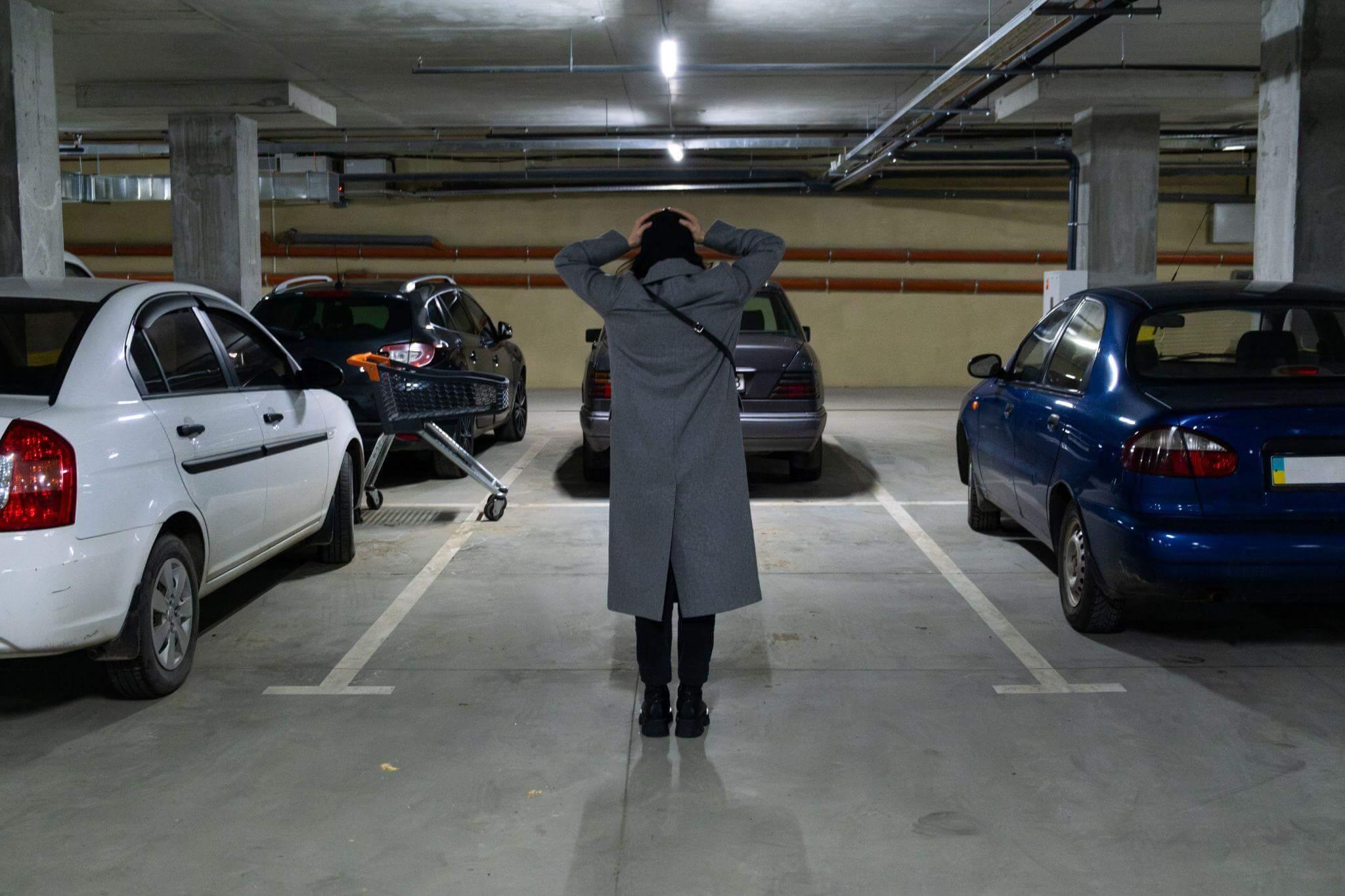 a woman standing in a parking garage next to parked cars