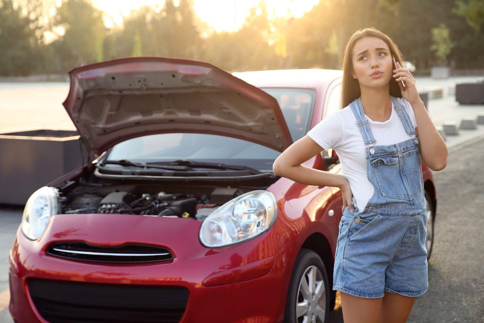 a pregnant woman standing next to a red car talking on a cell phone