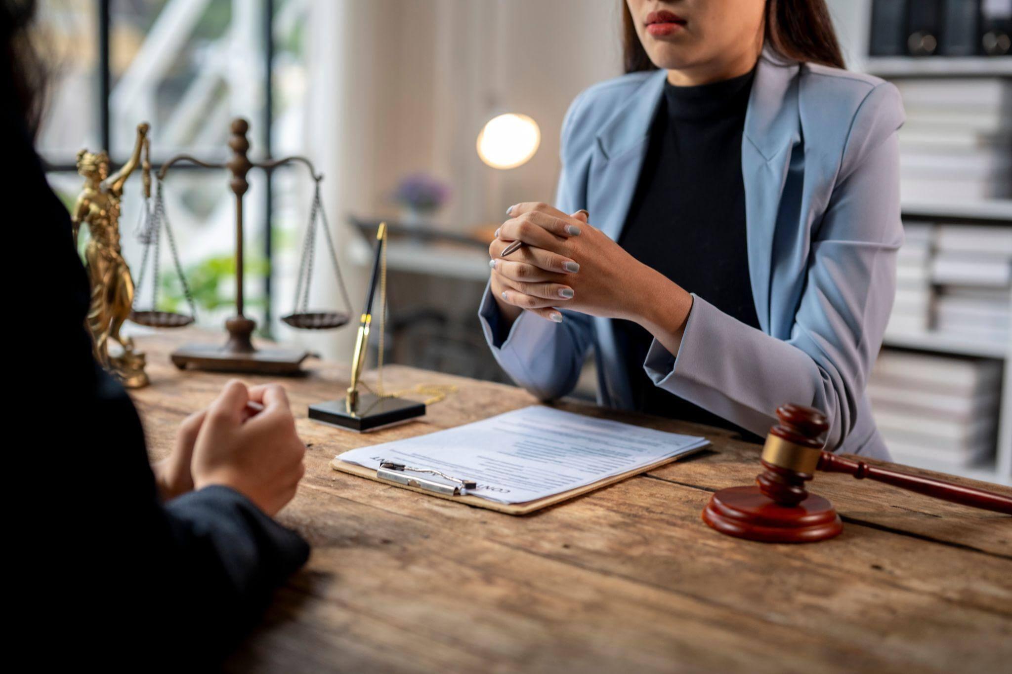 Personal injury lawyer consulting with a client at a desk with legal documents and scales of justice.