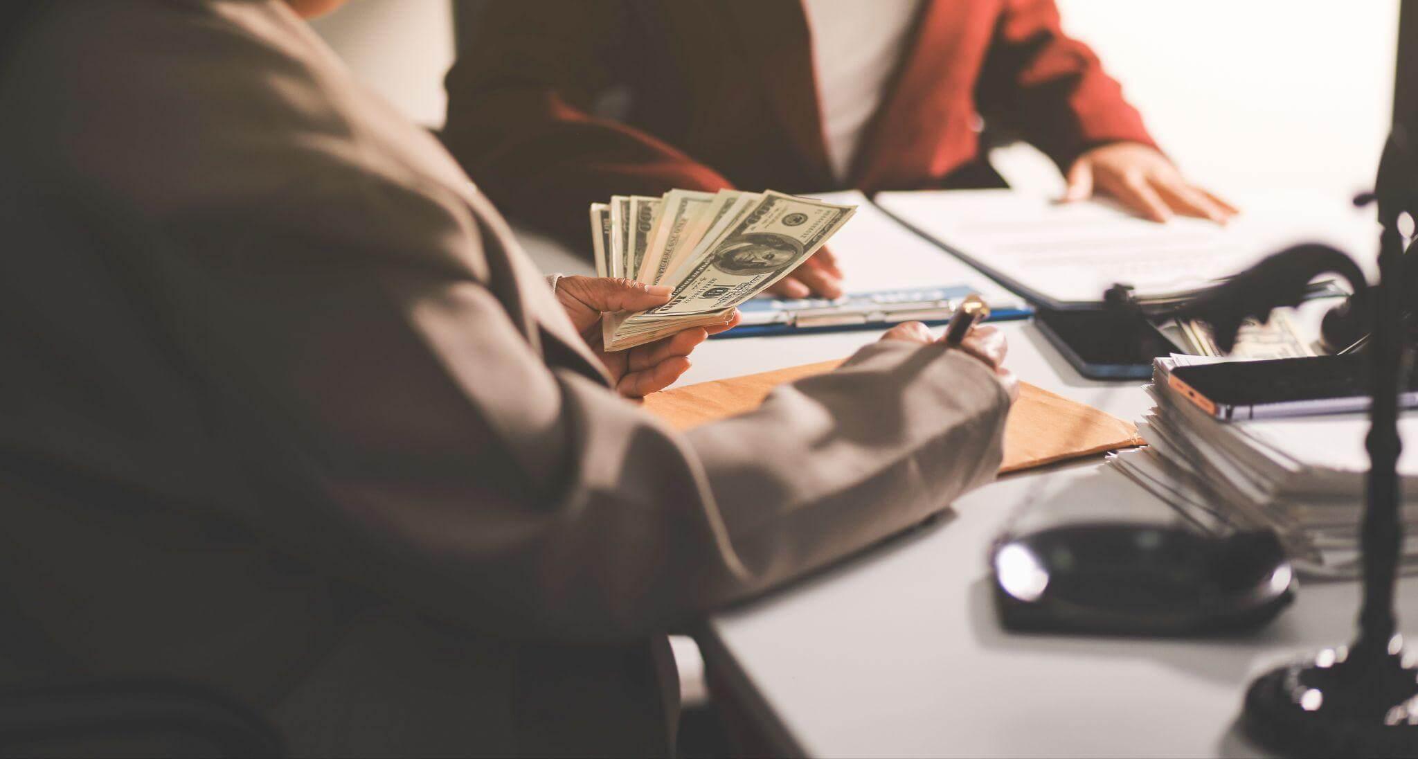Man holding money at a desk, representing compensation