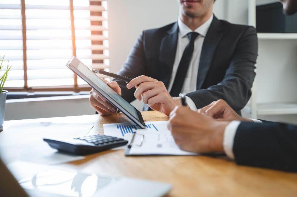 Two men working on a tablet, potentially discussing insurance