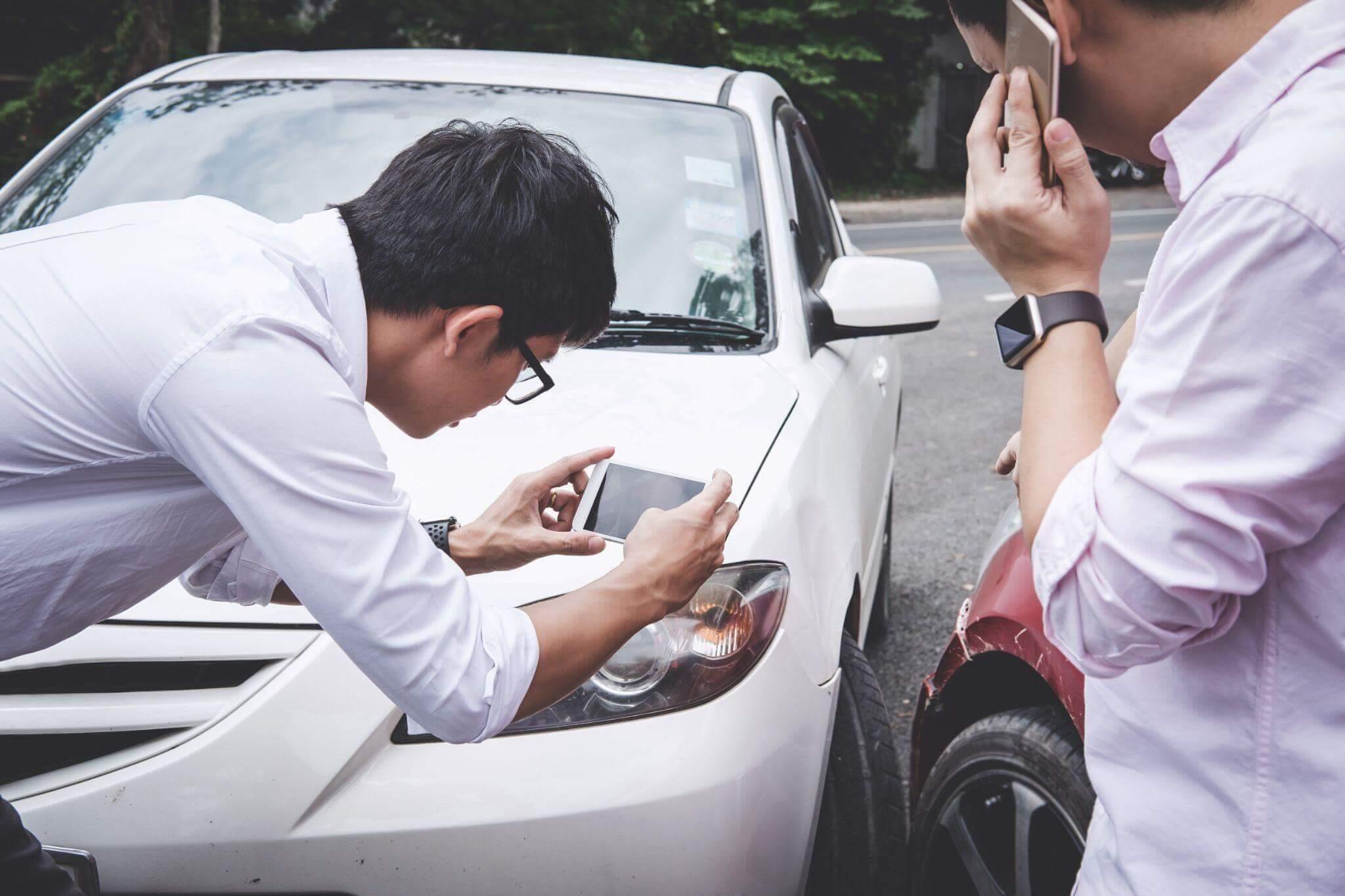 Man looking at cell phone next to car